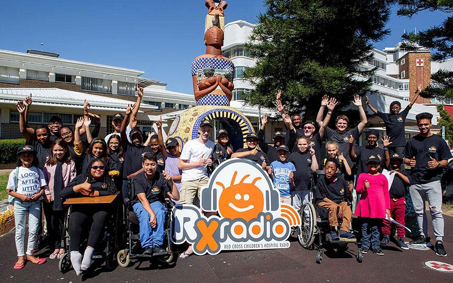 Group of people celebrating with RX Radio banner. 