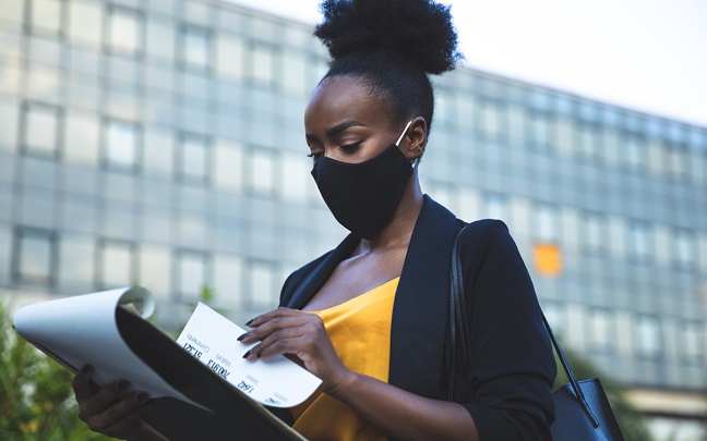 Woman in business walking out of the office wearing a black face mask
