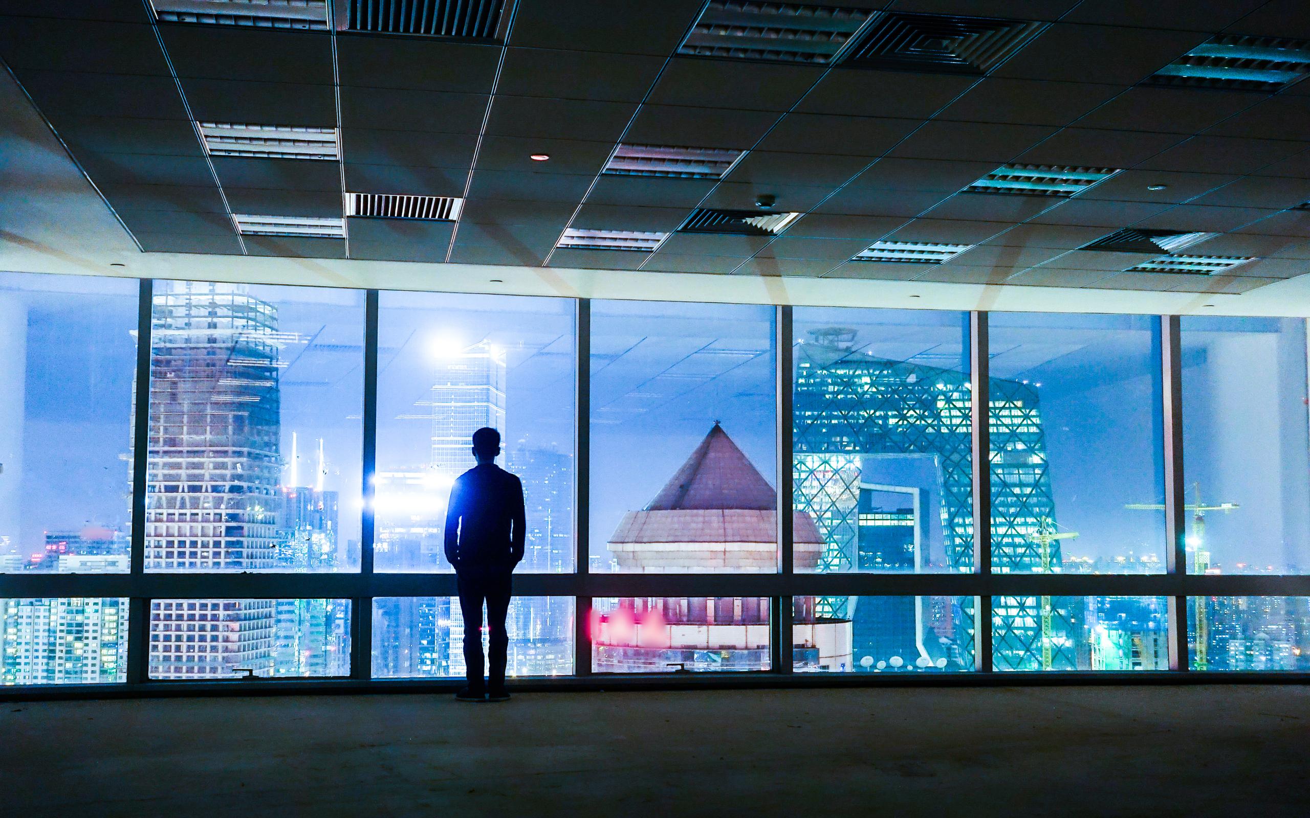 Man looking out of office windows at cityscape