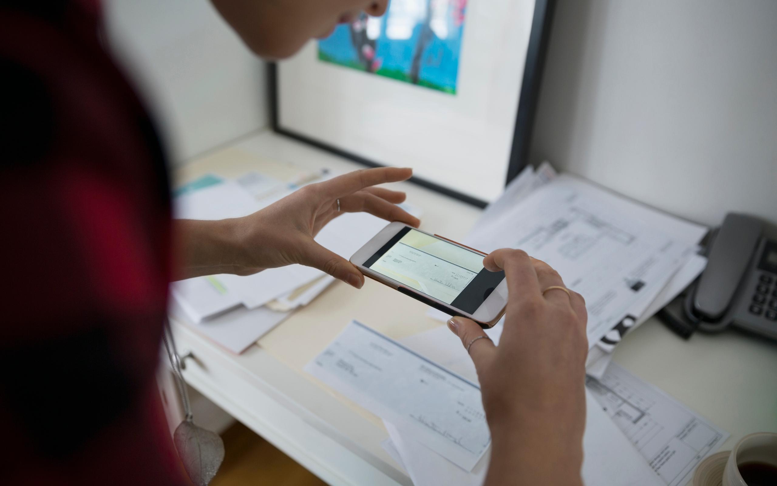 Woman photographing check with camera phone