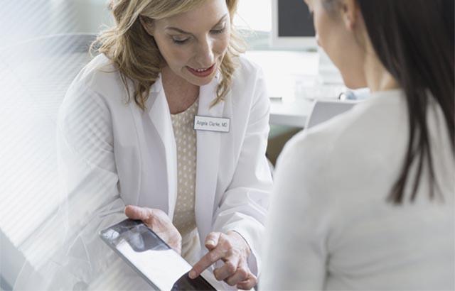 Doctor talking to a patient and pointing to something on a tablet