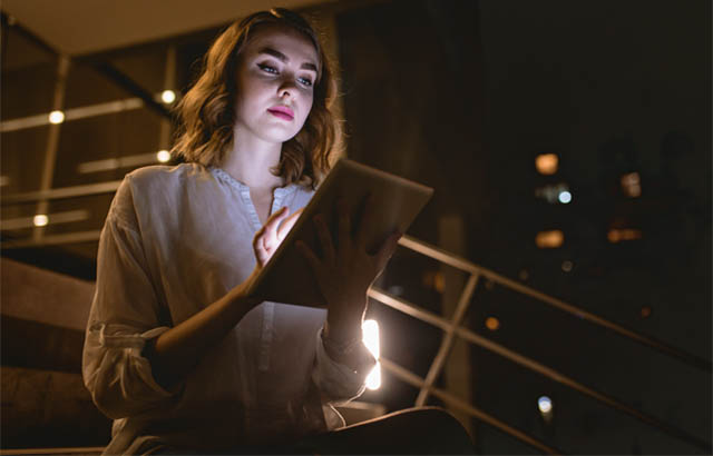 Woman using tablet in dark stairwell