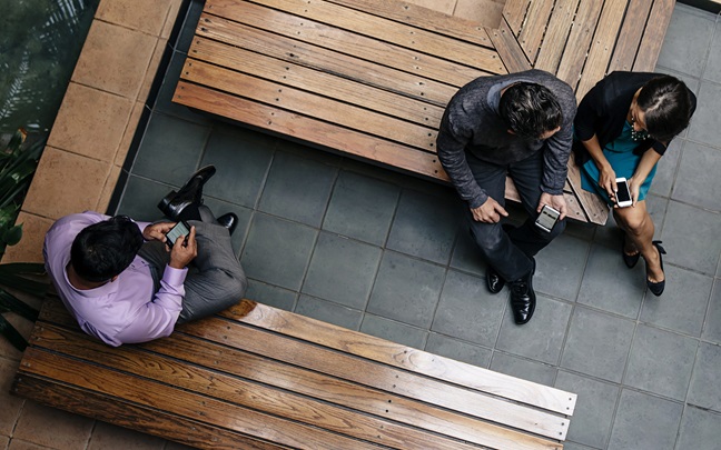 Aerial view of three business people sitting on benches