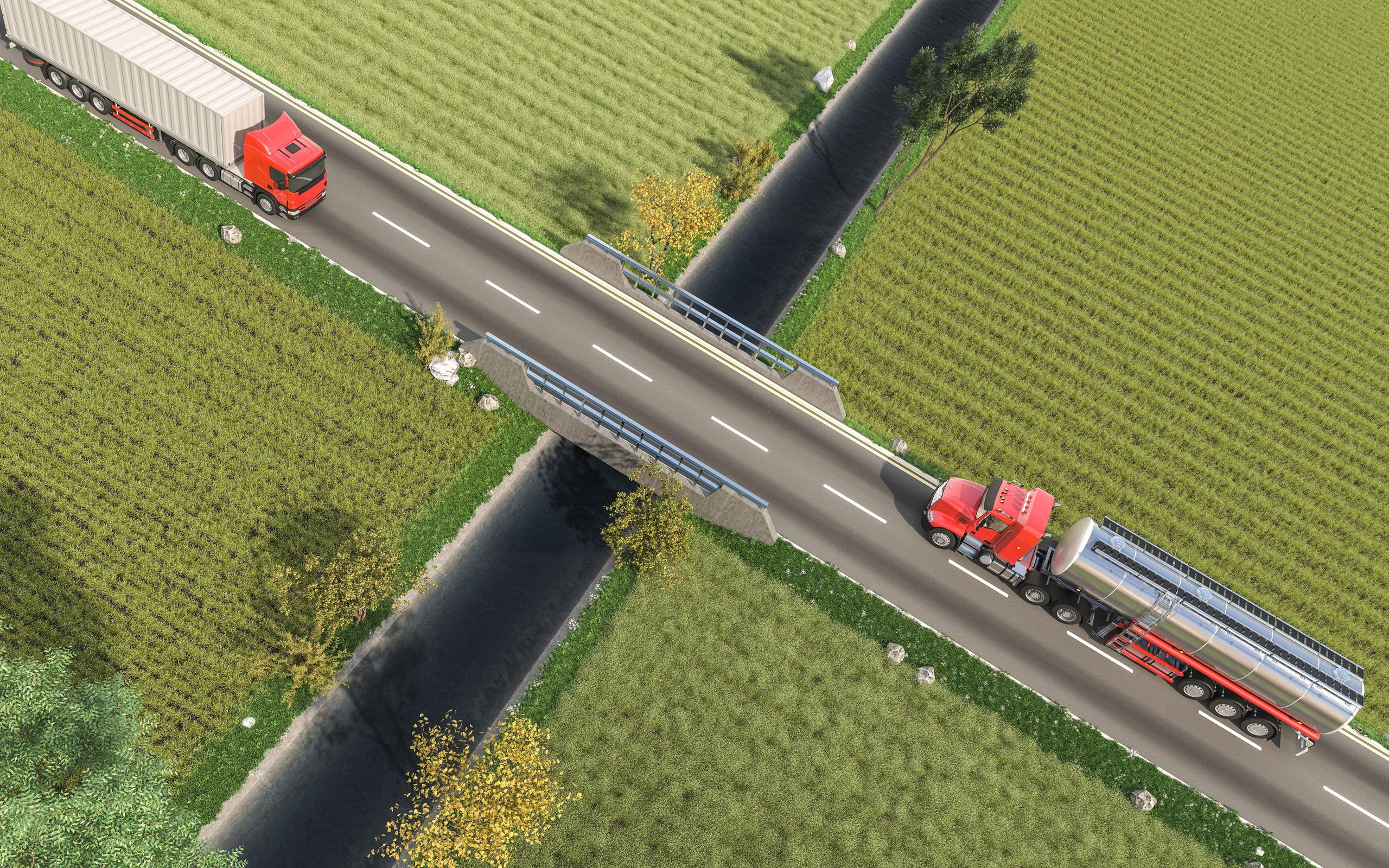 aerial view of trucks traveling on a highway surrounded by green fields