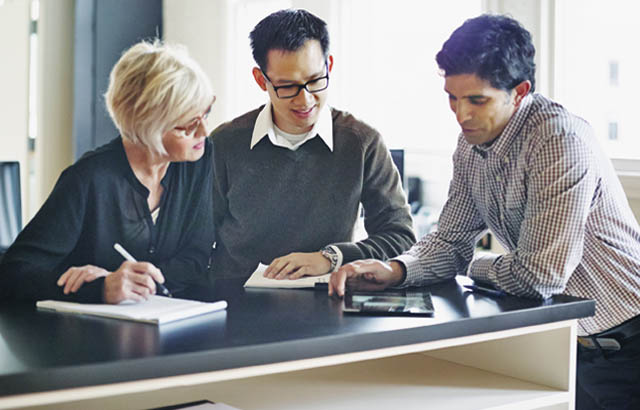 Three people in discussion over tablet